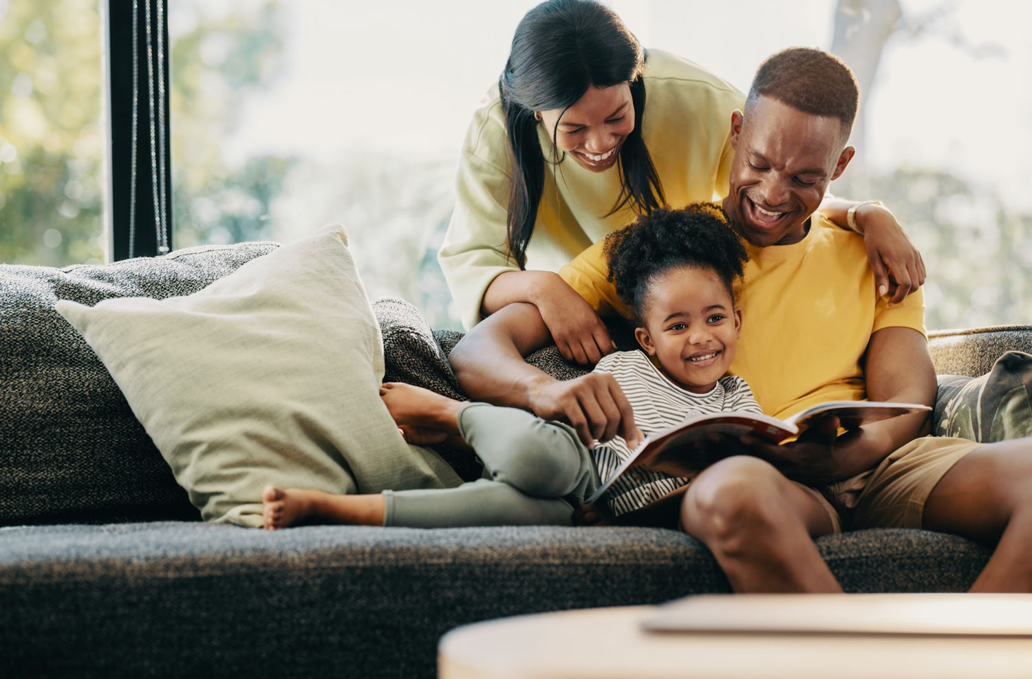 Happy little girl reading a story with her mom and dad.