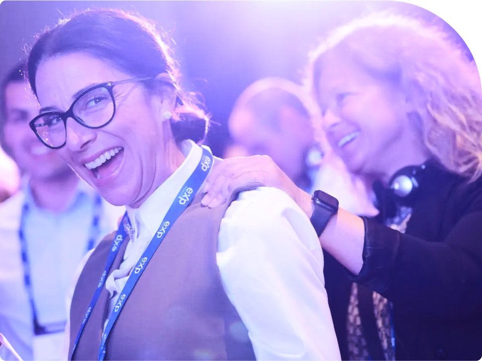 Attendees at a conference sharing a joyful moment under bright stage lights.